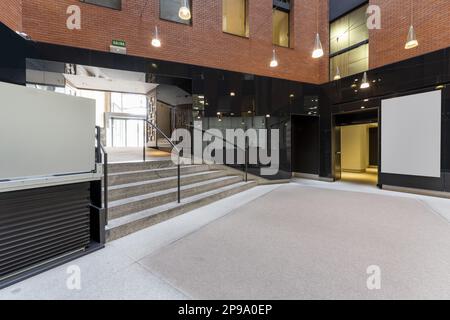 Atrium eines Bürogebäudes mit Granittreppen, Metallgeländern und Hängelampen Stockfoto