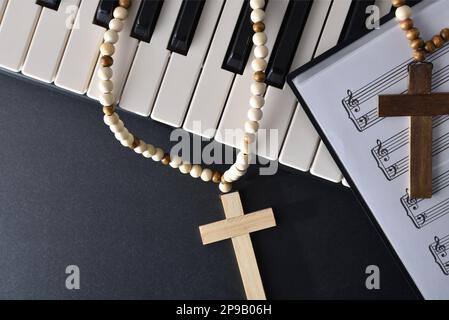 Religiöse Hintergrundmusik für Klavier mit Instrumenten- und Blattmusik mit Kreuzen oben auf dem schwarzen Tisch. Draufsicht. Stockfoto