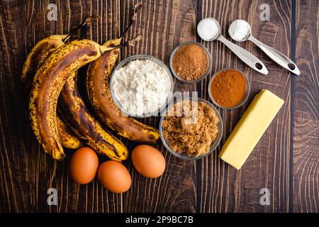 Braun-Butter Bananenbrot Zutaten auf einem rustikalen Holztisch: Reife Bananen, Mehl, brauner Zucker und andere rohe Zutaten Stockfoto