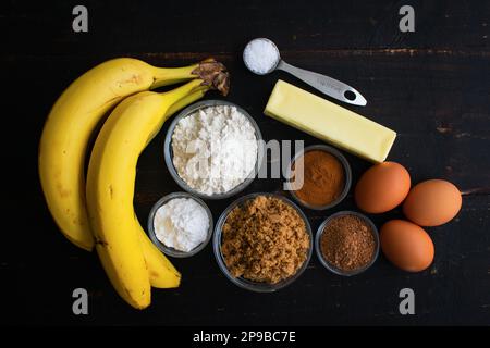 Braun-Butter Bananenbrot Zutaten auf einem rustikalen Holztisch: Reife Bananen, Mehl, brauner Zucker und andere rohe Zutaten Stockfoto