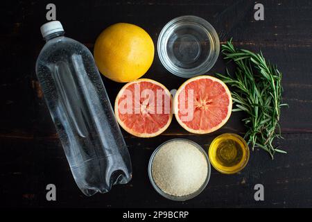 Honig Rosemary Grapefruit Soda Zutaten auf einem Holztisch: Rote Grapefruit, Honig, Mineralwasser und andere Zutaten auf dunklem Hintergrund Stockfoto