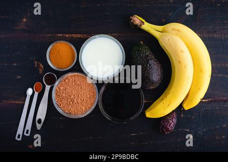 Kaffee und Mocha Smoothie Zutaten auf einem Holztisch: Kalter Kaffee, Kakaopulver, Bananen und andere Smoothie-Zutaten Stockfoto