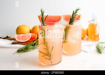 Honig Rosemary Grapefruit Sodas garniert mit Red Grapefruit: Alkoholfreie Sodas serviert in Dosen Gläsern mit Eiswürfeln Stockfoto