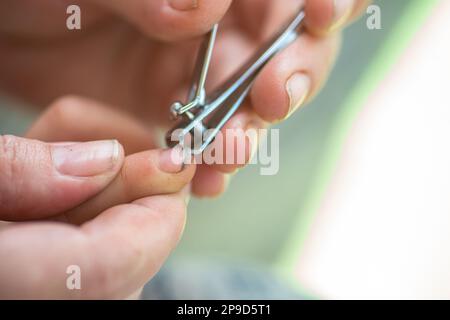 Routinemäßige mütterliche Betreuung. Pflege der Hände und Nägel des Kindes. Mom schneidet sehr dreckige Nägel des Babys mit einer Nagelzange ab. Stockfoto