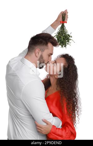 Ein glückliches Paar küsst sich unter Mistelzweigen auf weißem Hintergrund Stockfoto