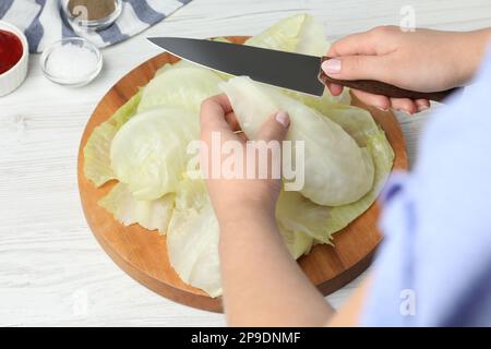 Eine Frau, die gefüllte Kohlrollen auf einem weißen Holztisch zubereitet, Nahaufnahme Stockfoto