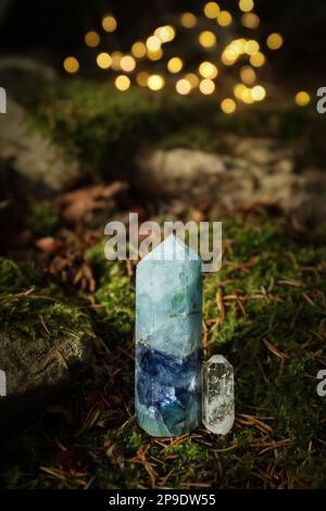 Wunderschöne Kristalle auf Moos gegen verschwommenes Licht Stockfoto