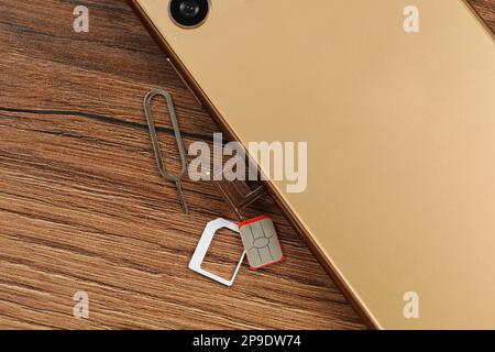 SIM-Karte, Mobiltelefon und Auswerfer auf Holztisch, flach liegend Stockfoto
