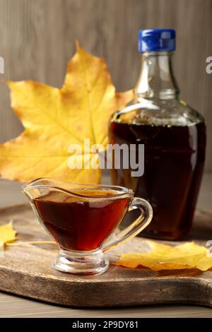 Flasche und Sauce mit leckerem Ahornsirup auf einem Holztisch Stockfoto