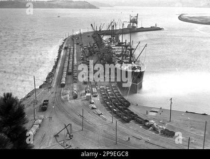 Schiffe laden am Hafen von Lyttleton, in der Nähe von Christchurch, Neuseeland, vermutlich in den 1930er Jahren. Stockfoto