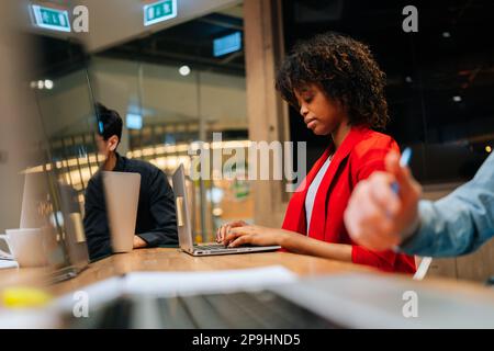 Selektiver Fokus auf fokussierte afroamerikanische Geschäftsfrau, die während der Arbeit von multikulturellen Geschäftsleuten am Schreibtisch am Laptop tippt Stockfoto