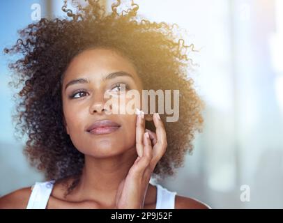 Sie verirrt sich immer in ihrer Hautpflege. Eine junge Frau, die ihr Gesicht im Bad mit Feuchtigkeit versorgt. Stockfoto