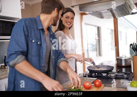 Ich helfe dir. Ein junges Paar, das zu Hause zusammen zu Abend isst. Stockfoto