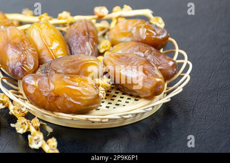 Nahaufnahme der algerischen königlichen Datteln auf einer Holzplatte auf schwarzem Hintergrund. Ramadan-Konzept. Stockfoto