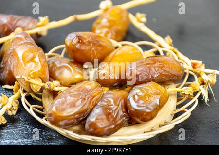 Nahaufnahme der algerischen königlichen Datteln auf einer Holzplatte auf schwarzem Hintergrund. Ramadan-Konzept. Stockfoto