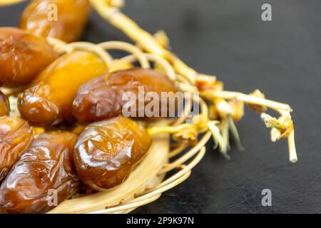 Nahaufnahme der algerischen königlichen Datteln auf einer Holzplatte auf schwarzem Hintergrund. Ramadan-Konzept. Stockfoto