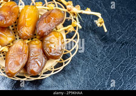 Nahaufnahme der algerischen königlichen Datteln auf einer Holzplatte auf schwarzem Hintergrund. Ramadan-Konzept. Stockfoto