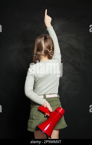Süßes kleines Mädchen, das Megafon gegen eine Tafel hält. Kind mit Lautsprecher Stockfoto