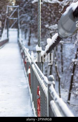 Vertikaler Panoramablick auf ein Metallkabel und ein Fußgängergeländer an einem Wintertag Stockfoto