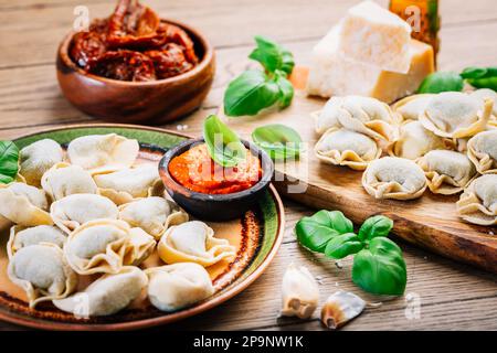 Hausmannskost - rohe Tortellini-Pasta mit Tomatenpesto und sonnengetrockneten Tomaten und Basilikum Stockfoto
