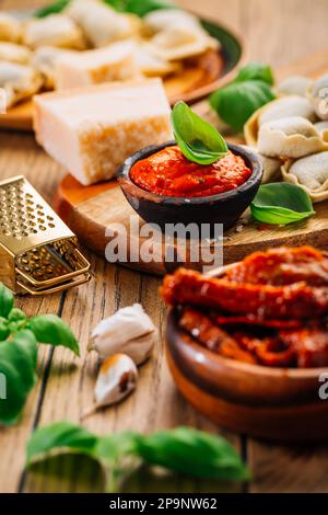 Hausmannskost - rohe Tortellini-Pasta mit Tomatenpesto und sonnengetrockneten Tomaten und Basilikum Stockfoto