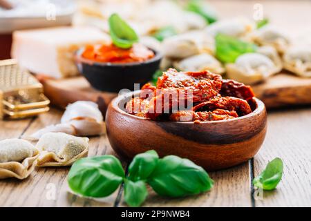 Hausmannskost - rohe Tortellini-Pasta mit Tomatenpesto und sonnengetrockneten Tomaten und Basilikum Stockfoto