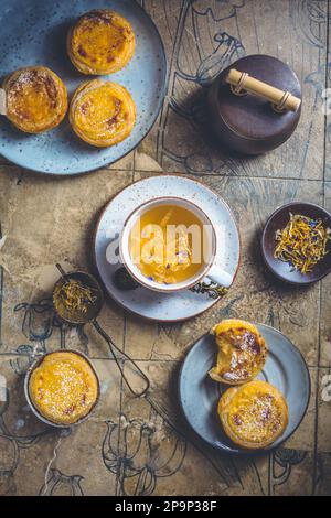 Pastel de nata mit einer Tasse Kräutertee, portugiesischem Süßei und Pudding-Gebäck Stockfoto