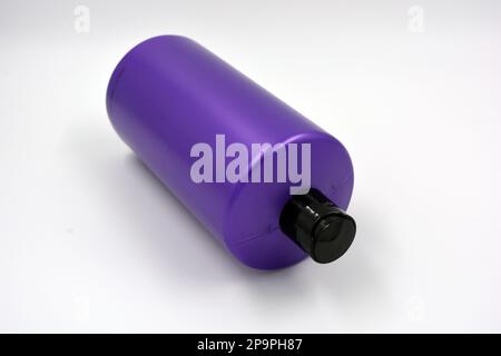 Eine große, runde Shampooflasche aus violettem Kunststoff mit schwarzem Deckel auf weißem Hintergrund. Stockfoto