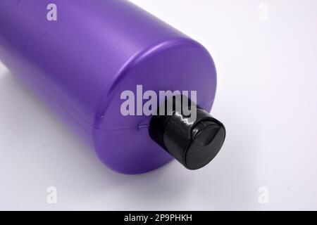 Eine große, runde Shampooflasche aus violettem Kunststoff mit schwarzem Deckel auf weißem Hintergrund. Stockfoto