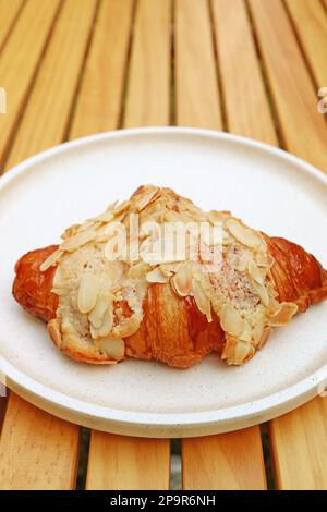 Köstliches französisches Mandel-Croissant-Gebäck auf einem Holztisch Stockfoto