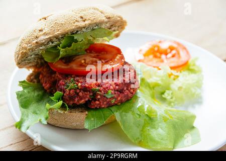 Veganer Burger auf einem Bun, der aus Beete, Quinoa und Linsen und rohen Hafer als Hauptzutaten hergestellt wird. Stockfoto