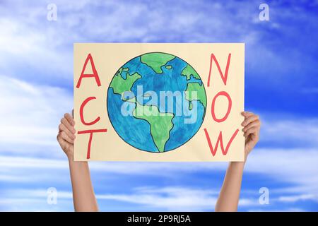 Der Demonstrante hält ein Plakat mit Text Act Now Against Blue Sky, Nahaufnahme. Klimaschutz Stockfoto