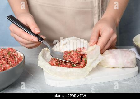 Eine Frau, die gefüllte Kohlrollen am hellgrauen Tisch zubereitet, Nahaufnahme Stockfoto