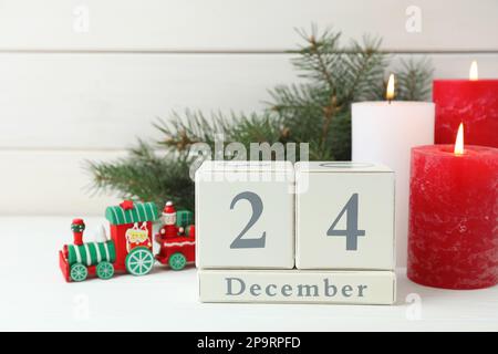 Heiligabend - 24. Dezember. Blockkalender und festliche Einrichtung auf weißem Holztisch Stockfoto