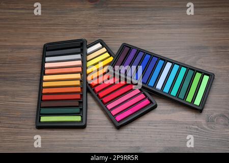 Bunte Pastelltöne in Tabletts auf Holztisch. Zeichenmaterialien Stockfoto