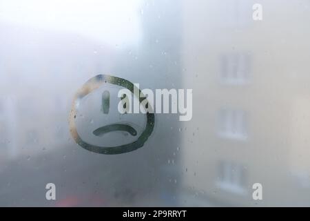Trauriges Gesicht auf nebligem Fenster, Platz für Text. Regenwetter Stockfoto