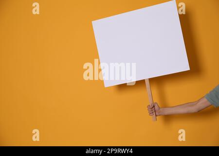 Frau mit leerem Schild auf gelbem Hintergrund, Nahaufnahme. Platz für Text Stockfoto