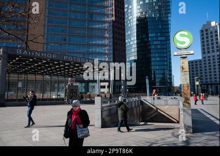 28.02.2023, Berlin, Deutschland, Europa - Menschen zwischen Hochhäusern und dem Eingang zur unterirdischen Tunnelstation am Potsdamer Platz. Stockfoto