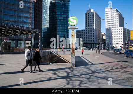 28.02.2023, Berlin, Deutschland, Europa - Menschen zwischen Hochhäusern und dem Eingang zur unterirdischen Tunnelstation am Potsdamer Platz. Stockfoto