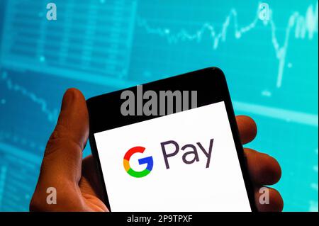 In diesem Foto wird das Google Pay-Logo der amerikanischen Online-Zahlungsplattform auf einem Smartphone mit einer Grafik des Börsenindex im Hintergrund angezeigt. Stockfoto