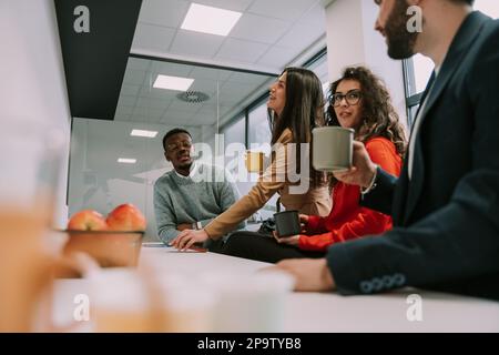 Vier wunderschöne, vielfältige Kollegen unterhalten sich während einer Pause von der Arbeit Stockfoto