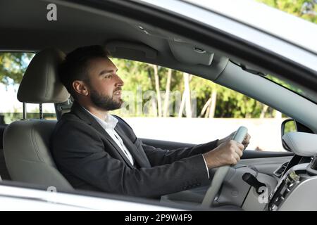 Attraktiver junger Fahrer im modernen Auto Stockfoto