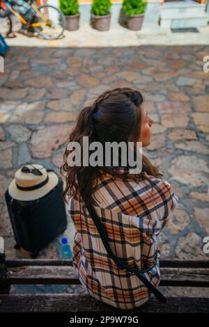 Eine wunderschöne Touristin sitzt auf einer Bank. Sie macht eine Pause Stockfoto