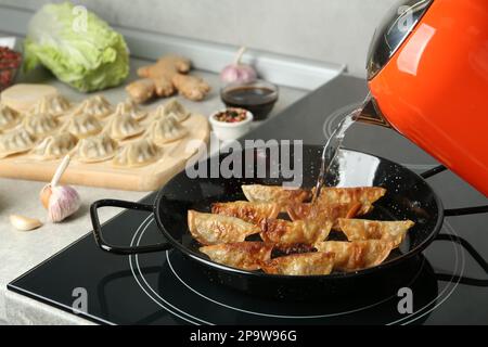 In der Küche Wasser auf die Pfanne mit Gyoza gießen Stockfoto