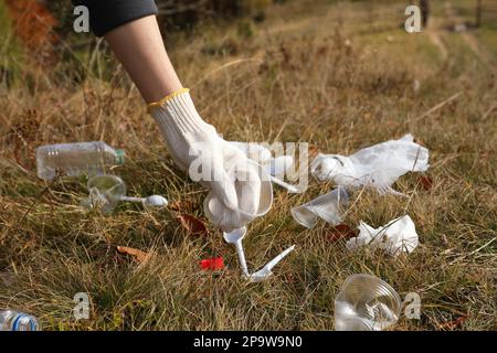 Eine Frau, die Müll in der Natur sammelt, eine Handschließung mit einem zerknitterten Becher Stockfoto