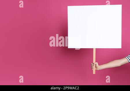 Frau mit leerem Schild auf rosa Hintergrund, Nahaufnahme. Platz für Text Stockfoto