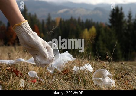 Eine Frau, die Müll in der Natur sammelt, eine Handschließung mit einem zerknitterten Becher. Platz für Text Stockfoto