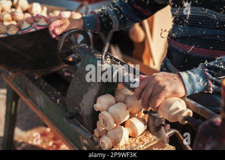 Handgefertigte Produktionsstufe des Spinning Top. Ein Holzschnitzer, der das Holz auf der alten Drehbank schnitzt. Stockfoto