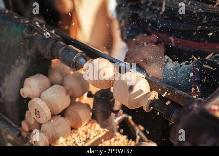 Handgefertigte Produktionsstufe des Spinning Top. Ein Holzschnitzer, der das Holz auf der Werkbank schnitzt. Stockfoto