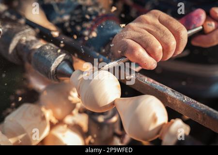 Handgefertigte Produktionsstufe des Spinning Top. Ein Holzschnitzer, der das Holz auf der alten Drehbank schnitzt. Stockfoto